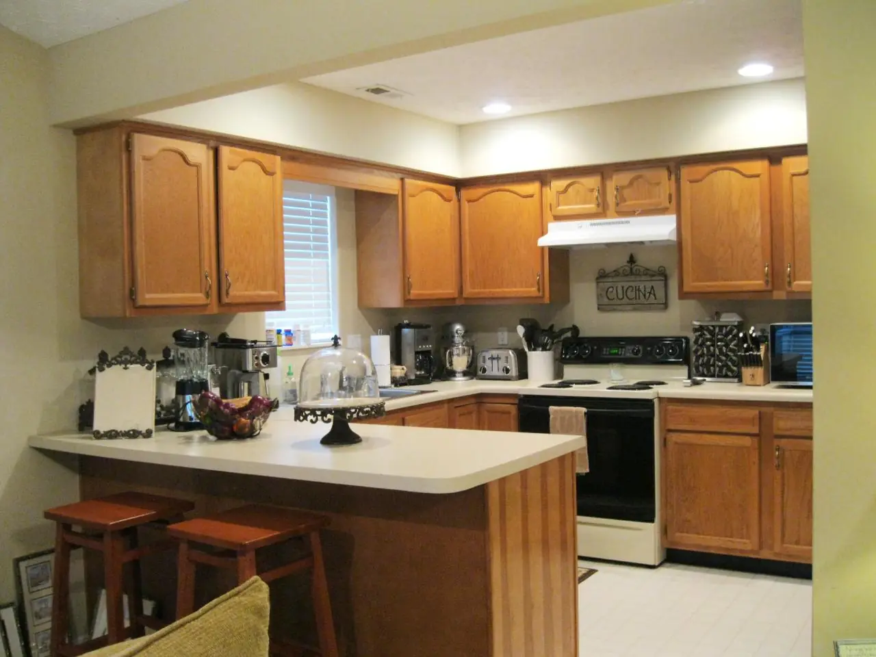Peninsula kitchen with orange-toned oak cabinets before respraying